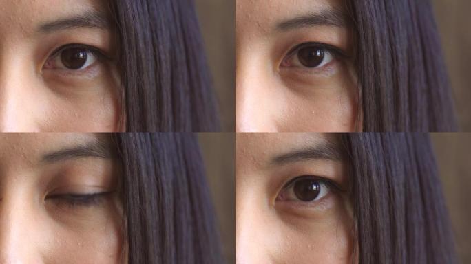 棕色眼睛的特写镜头，在思考想法时凝视着强烈而严肃的目光。亚洲女人眨眼向前看的面部细节。女人凝视或注视