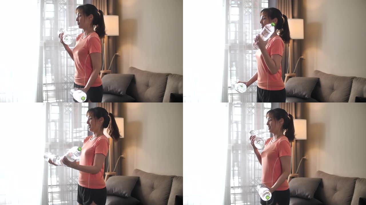 亚洲妇女在家中使用塑料水瓶代替健身房举重运动