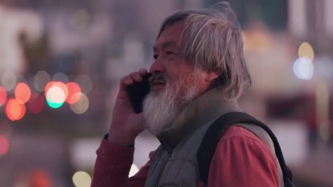亚洲资深男士，在城市户外用电话交谈，同意并站着。老年男性，成熟男性和智能手机聊天，在外面交流和讨论，