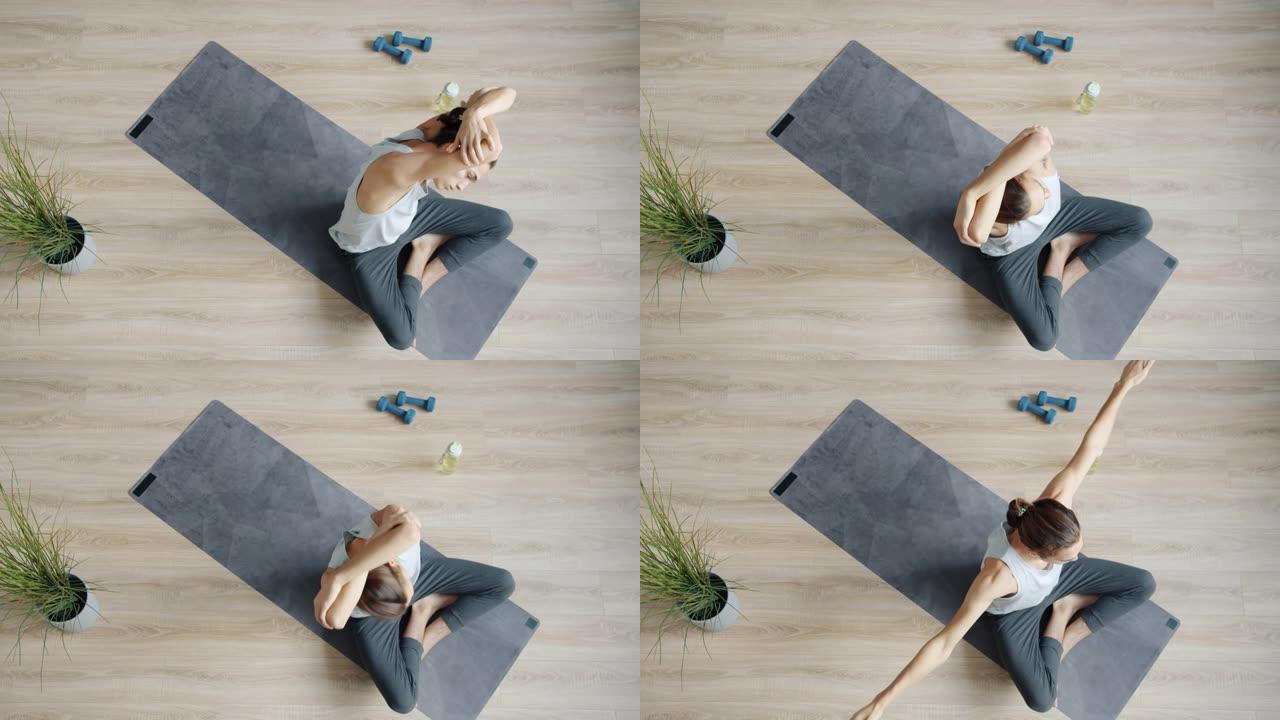 现代工作室瑜伽教练训练的慢动作俯视图在瑜伽垫上伸展身体