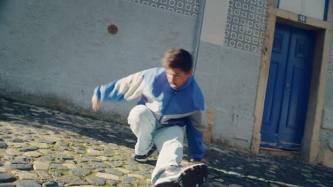 慢动作拍摄的一个年轻的成年拉丁男子穿着时髦的衣服，在一个城市的老城区的街道上主动跳霹雳舞。在安静的小
