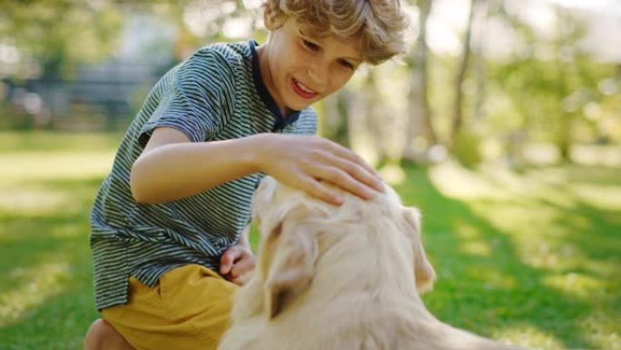 小男孩和他忠诚的金毛猎犬一起玩，抓挠他的头，爱抚，拥抱。阳光明媚的一天，在户外玩得开心