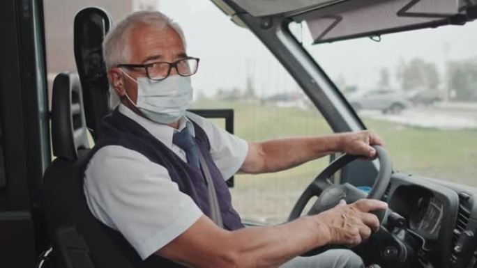 驾驶员座位上戴着口罩的高级公共汽车司机肖像