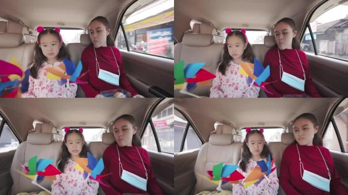可爱的亚洲小女孩和她的妹妹在汽车座椅的后面