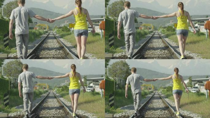 慢动作: 夫妻在铁轨上行走时牵手