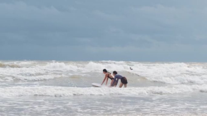 年轻女孩和教练一起学习冲浪