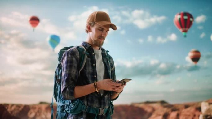年轻英俊的旅游山地徒步旅行，背包在大自然中。男性冒险家背包客在岩石峡谷山谷上使用智能手机。国家公园热