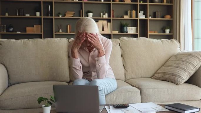 沮丧的成熟女人管理财务，感到压力沉重的银行债务