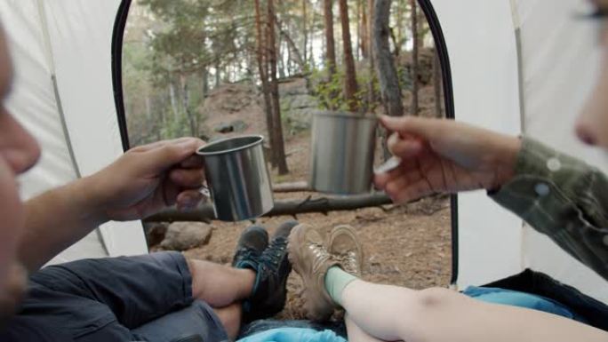 快乐的一对男女在帐篷里碰碰金属杯一起享受露营