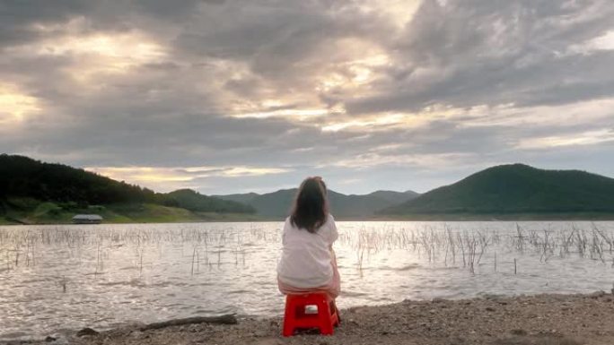 小女孩在日落时在湖边放松
