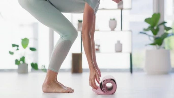 女人在瑜伽健身训练室的地板上铺开瑜伽垫。积极健康的赤脚女性准备家庭锻炼，以平衡的身心过上健康的生活方