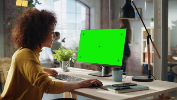 创造性的多民族女性在台式电脑上工作，绿屏模拟显示。快乐的项目经理浏览互联网，编写任务，为合作伙伴制定
