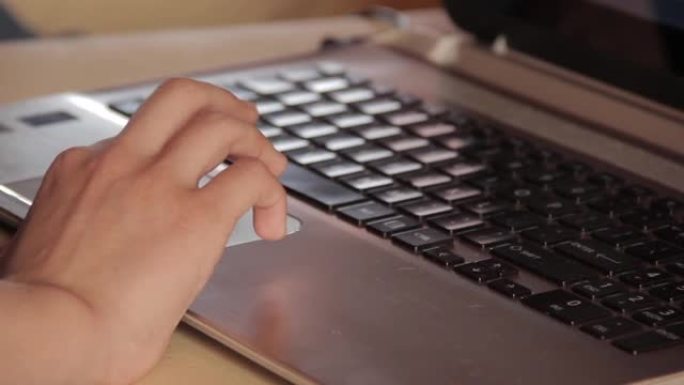 手放在电脑键盘上，年轻的女性手在黑色键盘的银色笔记本电脑触摸板上工作。特写。