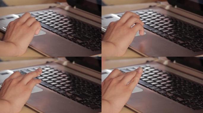 手放在电脑键盘上，年轻的女性手在黑色键盘的银色笔记本电脑触摸板上工作。特写。