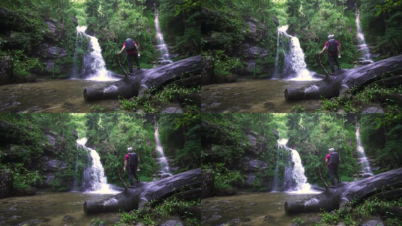 亚洲男子在泰国清迈的热带瀑布上旅行并伸展双臂