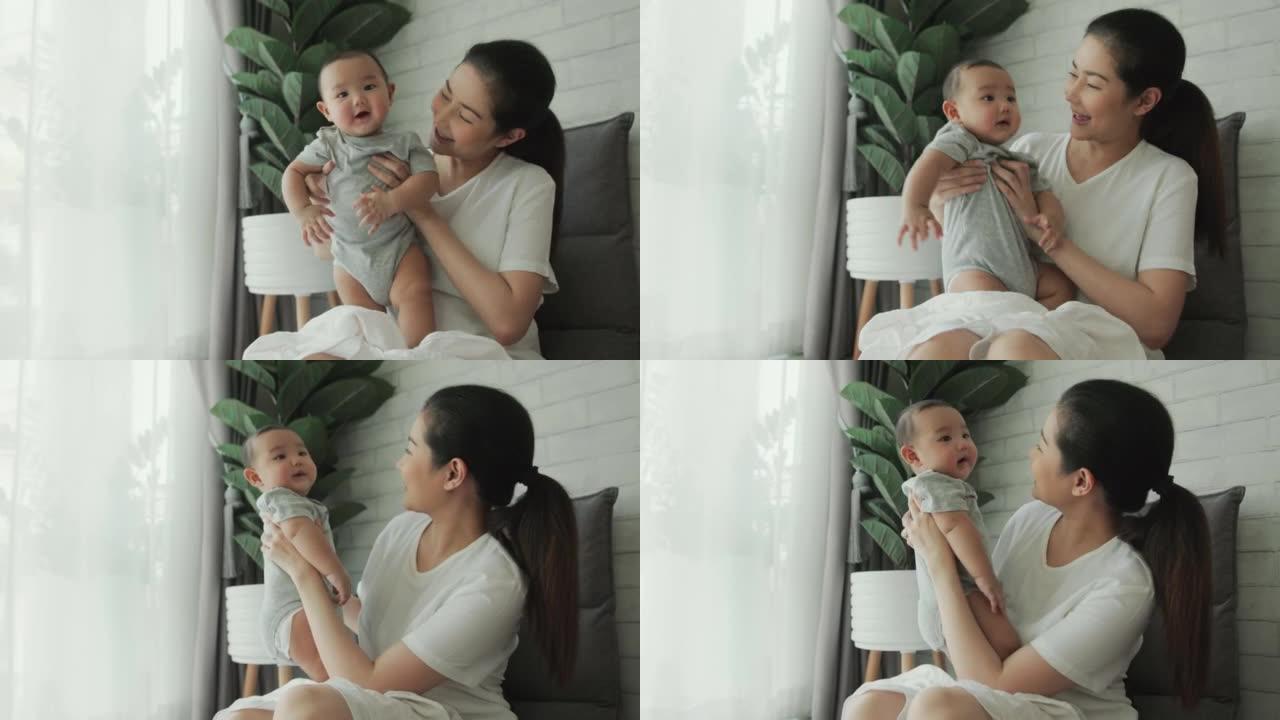快乐的成年亚洲妈妈在家里抱着和她可爱的新生男婴玩耍。玩耍有助于建立牢固的关系