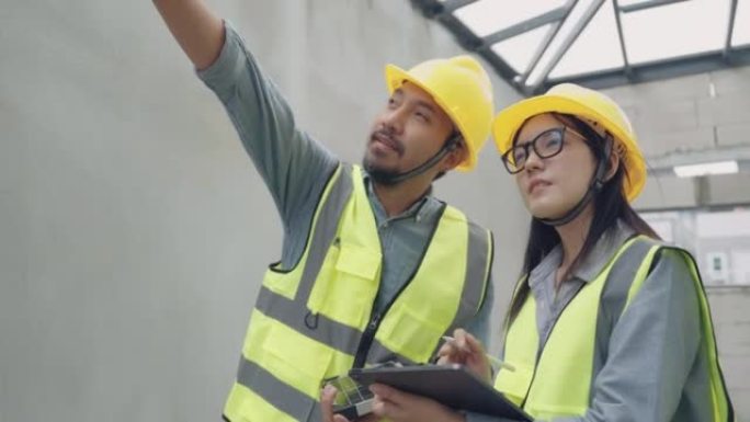 亚洲女建筑师工程师在施工现场与男工程师交谈安装太阳能电池板