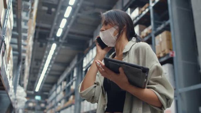年轻的亚洲女商人在线卖家戴着口罩，在零售购物中心的电话平板电脑支架上与客户确认订单。