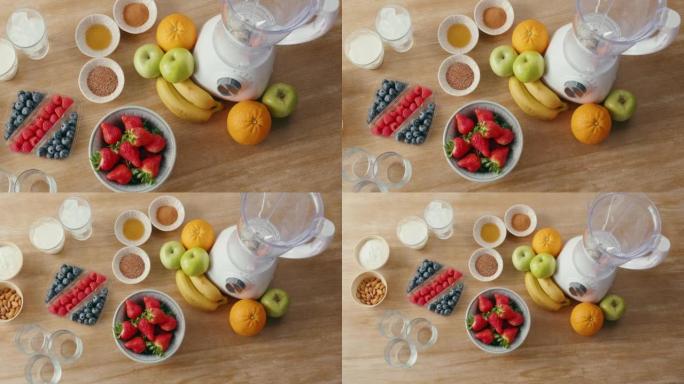 木桌上的新鲜农产品和健康奶昔配料的俯视图。水果，杏仁和其他成分以及用于制作冰沙的搅拌机。健康节食和营