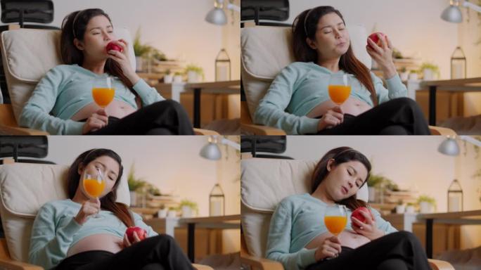 快乐孕妇在家吃一个新鲜的红苹果，喝橙汁。