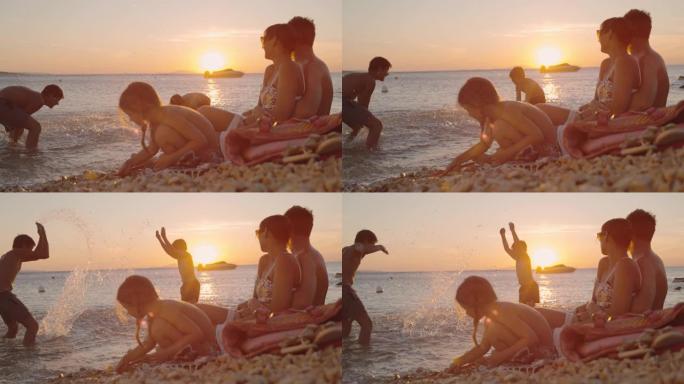 超级SLO MO家庭，三个孩子在日落时在海滩上放松