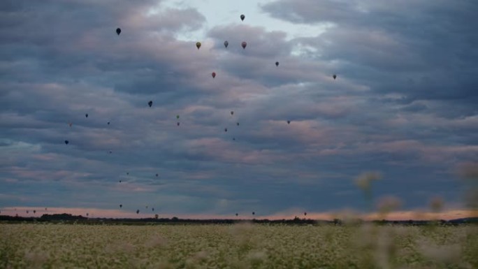 黎明时分，热气球在多云的天空中飞越乡村