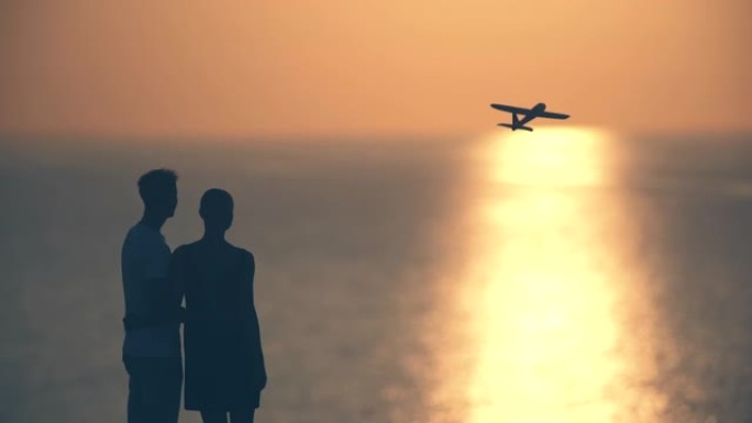 这对夫妇把玩具飞机扔在日落背景上。慢动作