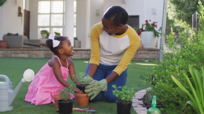 快乐的非洲裔美国母女园艺，在花园里种植植物