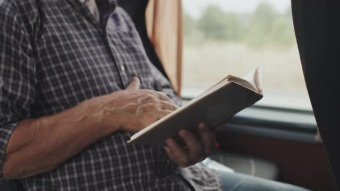 乘公共汽车时男子阅读书籍的中部
