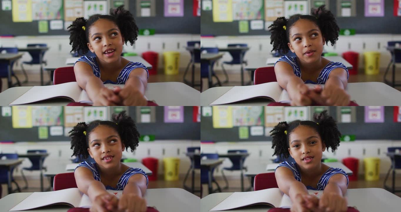 快乐的混血女学生的肖像坐在教室里，回答问题，看着相机