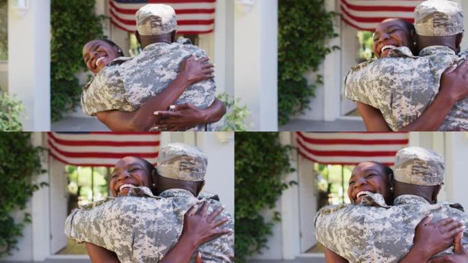 非裔美国士兵拥抱微笑的妻子在美国国旗前的房子