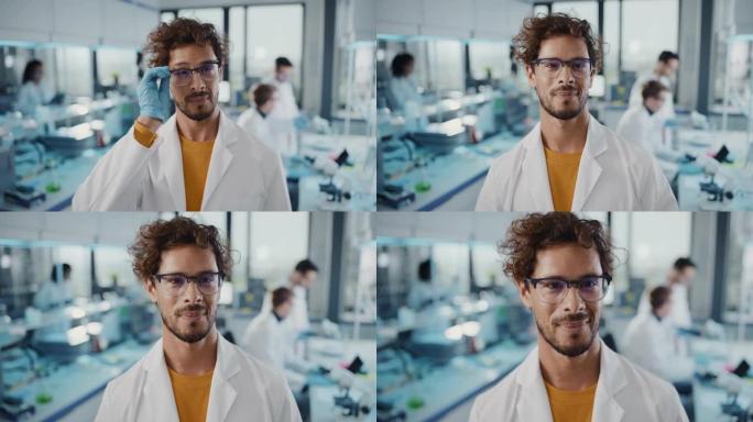 医学科学实验室: 穿着白色外套的年轻拉丁科学家戴上眼镜，交叉双臂，看着相机微笑。多元化的专家团队。中