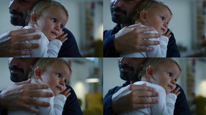 一个年轻快乐的微笑父亲的电影特写镜头将他的儿子蹒跚学步的男婴抱在怀里，拥抱着他，同时在家里享受时光。