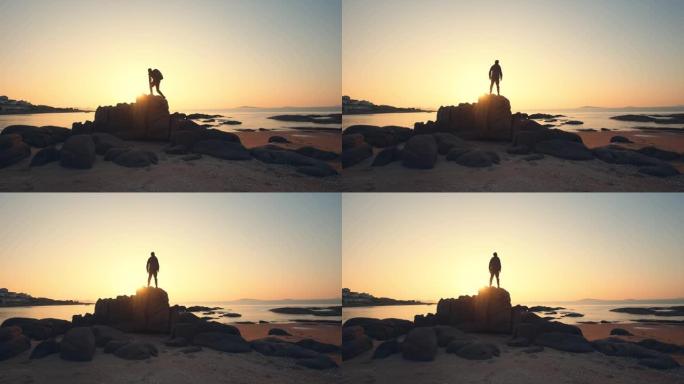 站在岩石上看海上日出的年轻人