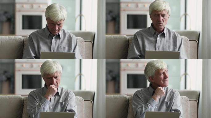 年长的沉思认真的专心男人坐在笔记本电脑的沙发上