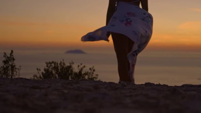 SLO MO在日落时，穿着白色连衣裙的女子欣赏迷人的海景