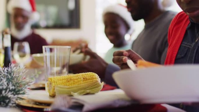 非裔美国女孩坐在餐桌上一起吃午饭，在盘子里端着食物