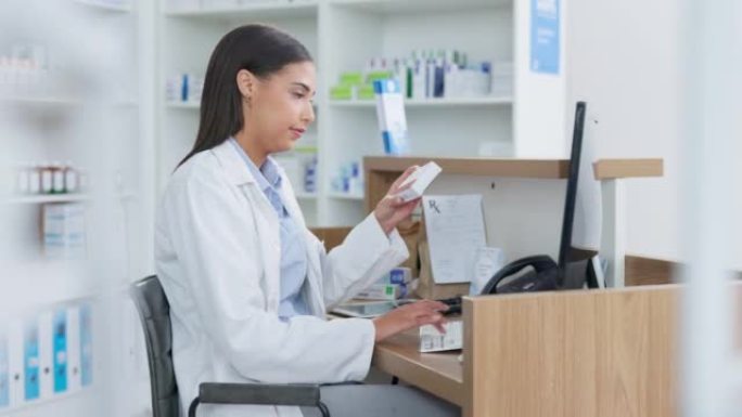 年轻的药剂师在药房柜台上电脑工作。妇女使用技术访问药物数据库，进行库存检查并在药店分发在线药物处方
