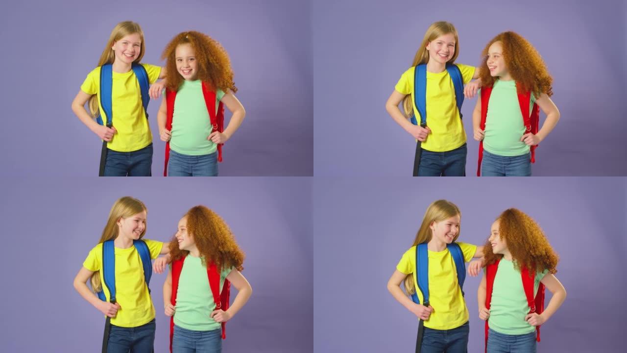 两个女孩穿着背包去紫色背景上学的工作室镜头 -- 慢动作镜头