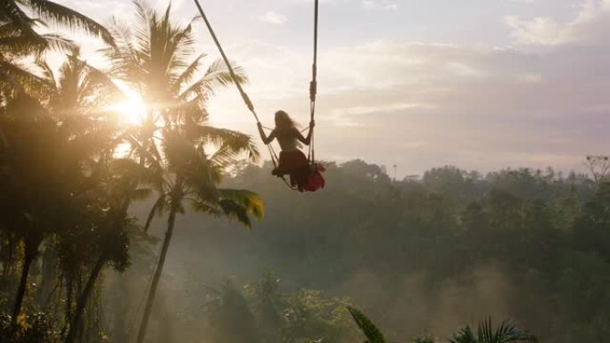 幸福的女人在日出时在丛林中摇摆旅行女孩享受异国情调的假期，在热带雨林假日生活方式自由中，阳光照耀着棕