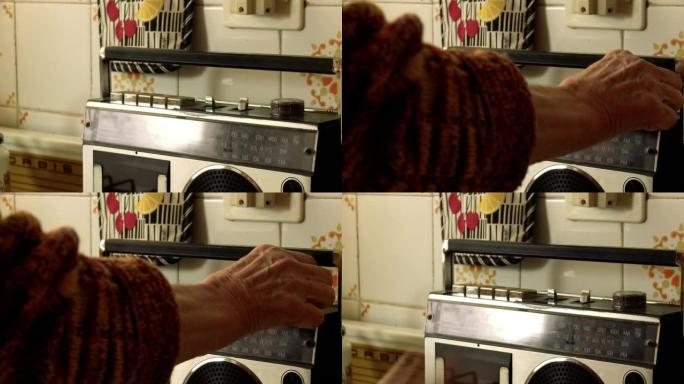 一位老妇在厨房里调音旧收音机的手。特写。