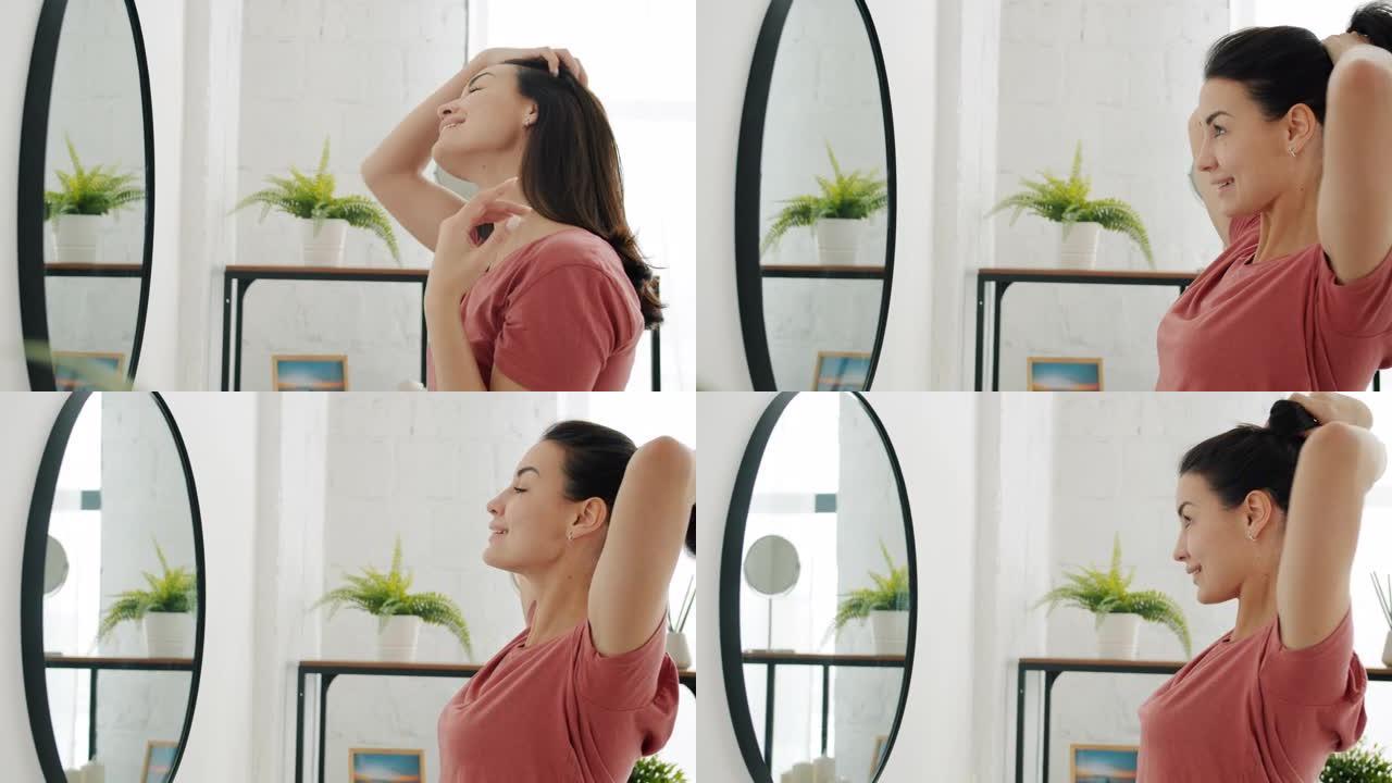 现代浴室中好看的女人选择发型照镜子的侧视图