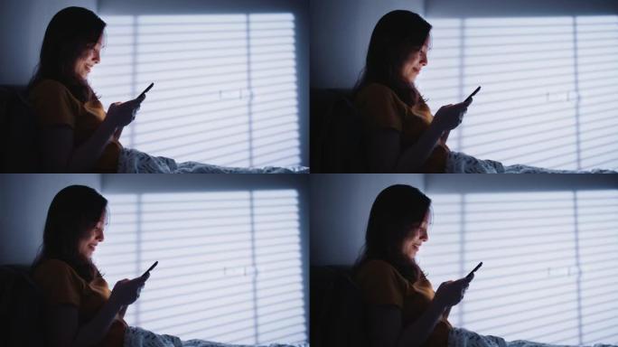 亚洲女子晚上在床上使用手机