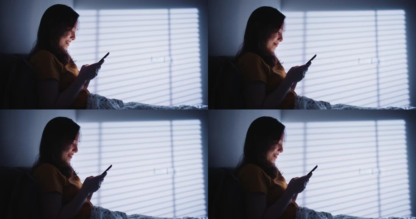 亚洲女子晚上在床上使用手机