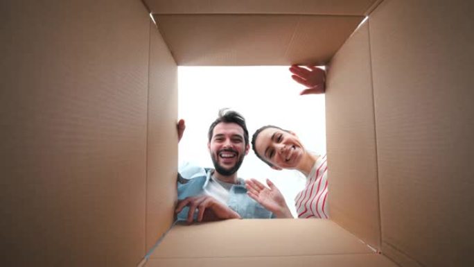 幸福的夫妇透过纸箱看着相机。