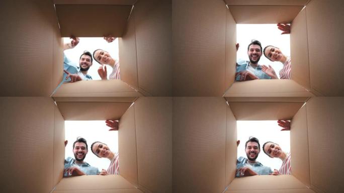 幸福的夫妇透过纸箱看着相机。