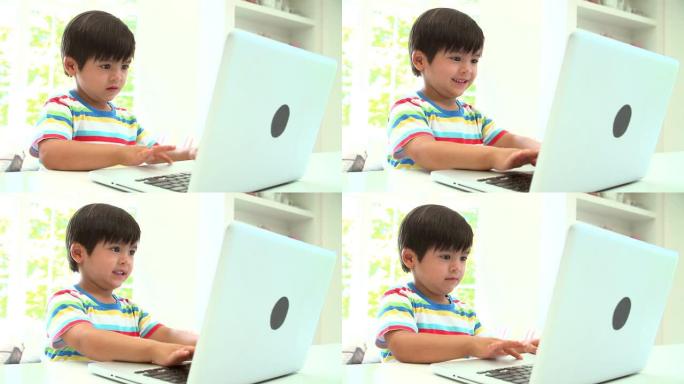 年轻的亚洲男孩在家里使用笔记本电脑