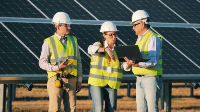工程师们正在讨论太阳能能量学的一个项目。可再生能源、太阳能发电厂、绿色电力概念。