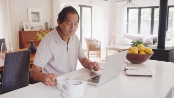 退休，年老而富有的前亚洲金融工作者在现代房屋中的笔记本电脑上进行研究。中国老年男性养老金领取者在计算