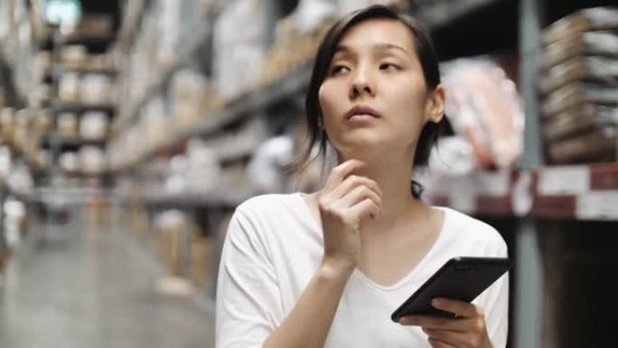 亚洲妇女在仓库和使用智能手机检查价格